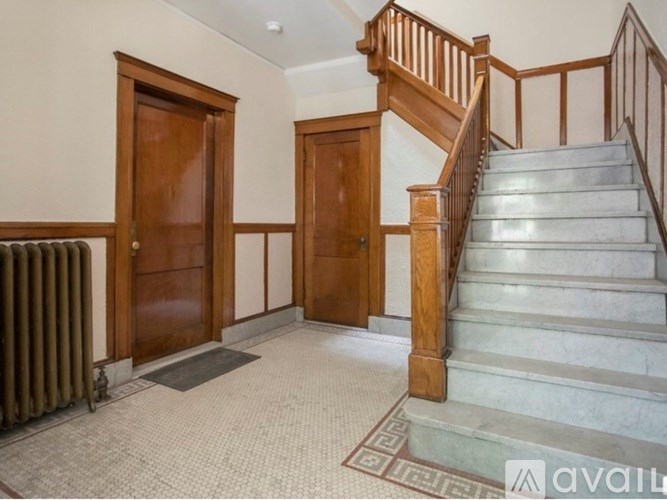 A hallway with a staircase, two doors, and a radiator.