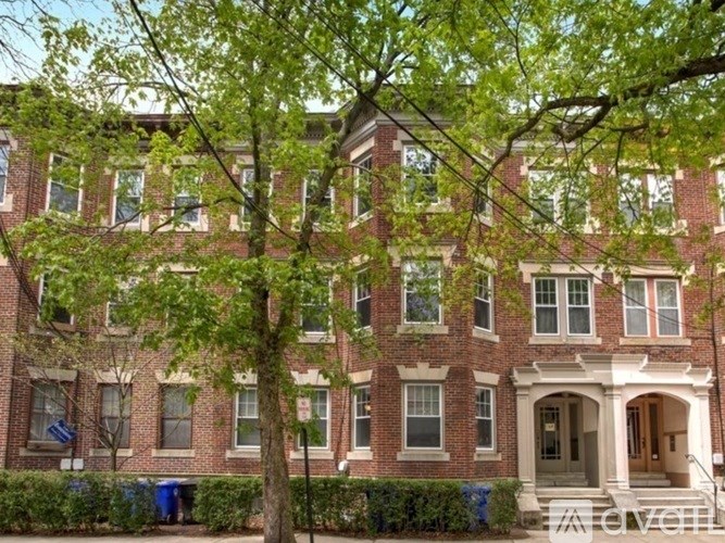 A large red brick building with a tree in front.