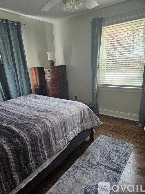 A bedroom with a bed, dresser, and window with blinds.