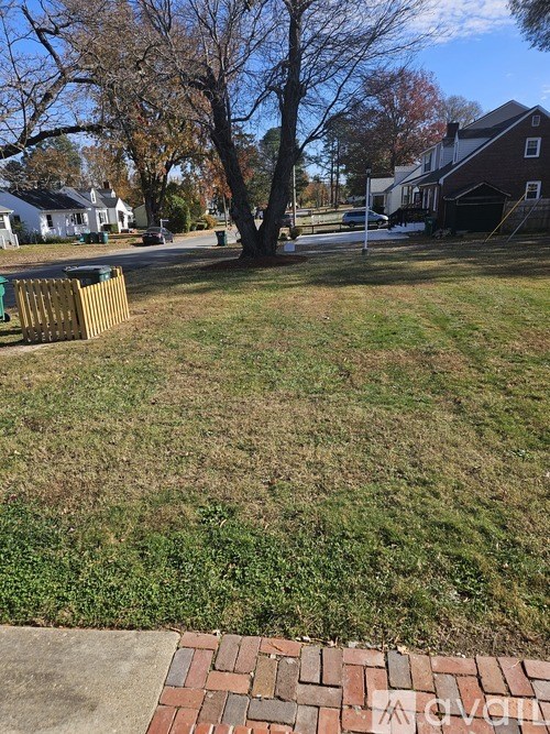 A tree in a yard with a house in the background.