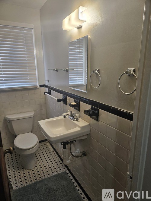 A bathroom with a toilet, sink, and mirror.