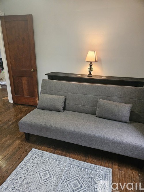 A grey couch with a lamp on the side table.