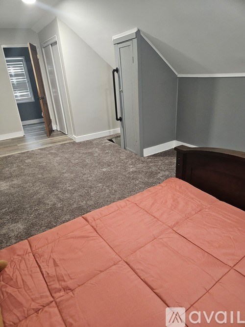 A bedroom with a bed covered in a pink comforter.
