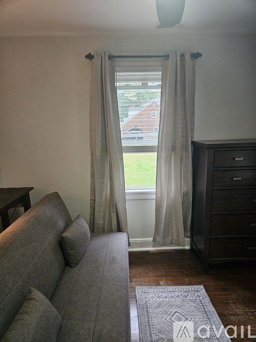 A grey couch sits in front of a window with curtains.
