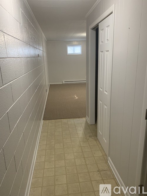 A hallway with white walls and a tiled floor.