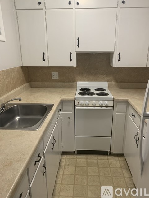 A kitchen with white cabinets and a stove top oven.
