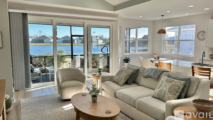 A living room with a couch, chairs, and a view of the water.