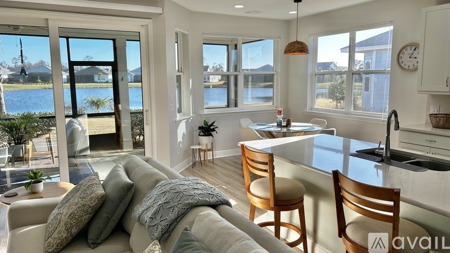 A living room with a couch, chairs, and a view of a lake through the windows.