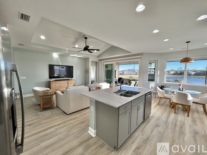 A modern kitchen with a refrigerator, sink, and a television.