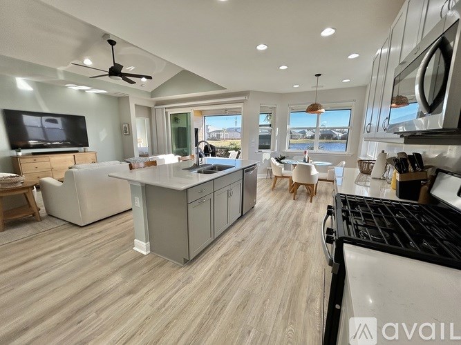 A modern kitchen with a large island and a flat screen TV.