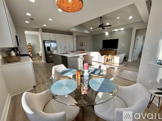 A modern kitchen with a glass dining table and white chairs.
