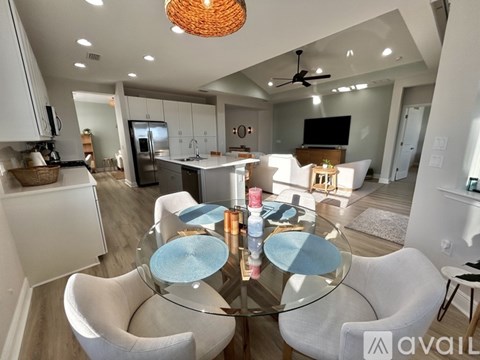 A modern kitchen with a glass dining table and white chairs.