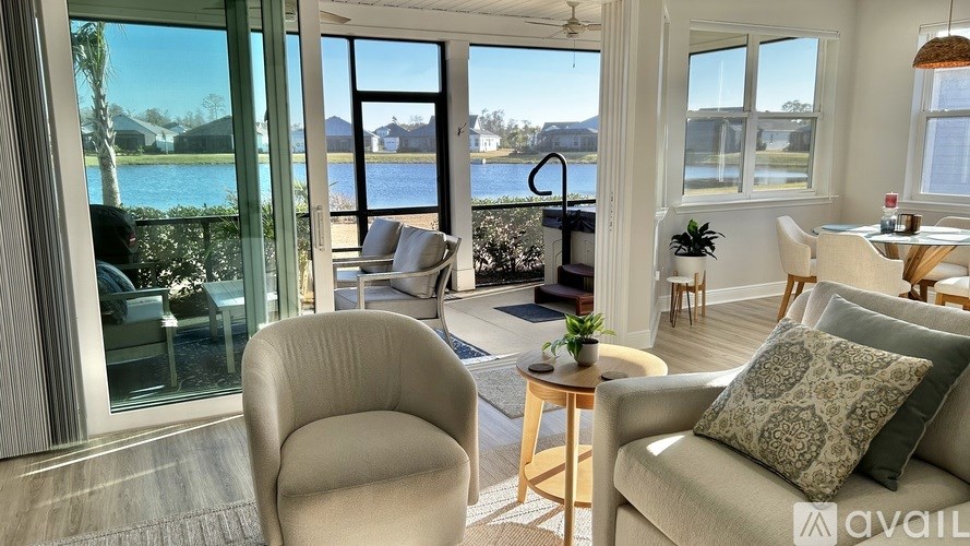 A living room with a view of a lake and houses across the way.