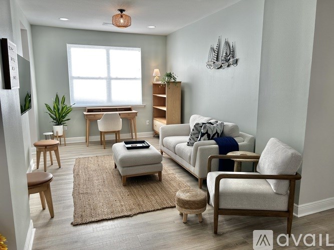 A living room with a couch, chair, ottoman, and a rug.