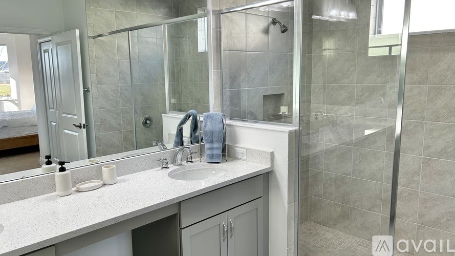 A bathroom with a sink, mirror, and shower.