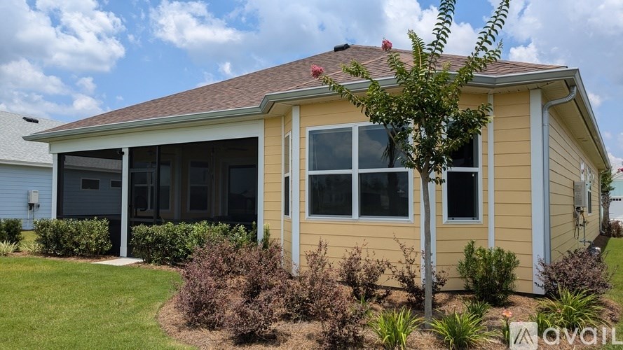 A house with a yellow exterior and a tree in front of it.