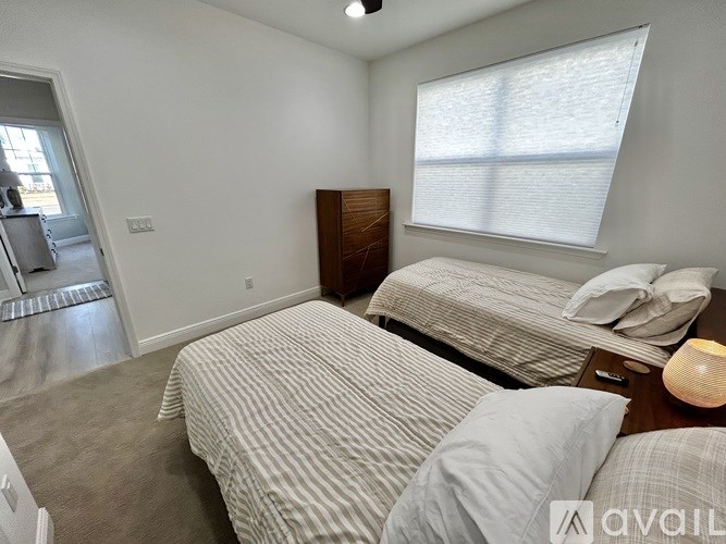 A bedroom with two beds and a nightstand with a lamp on it.