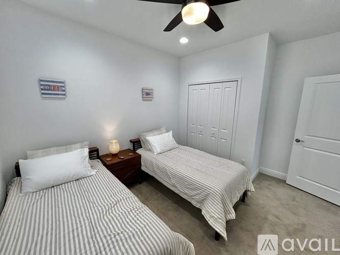 Two beds in a room with a ceiling fan.