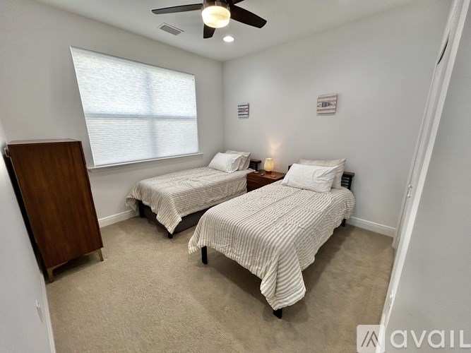 Two twin beds in a room with a ceiling fan.