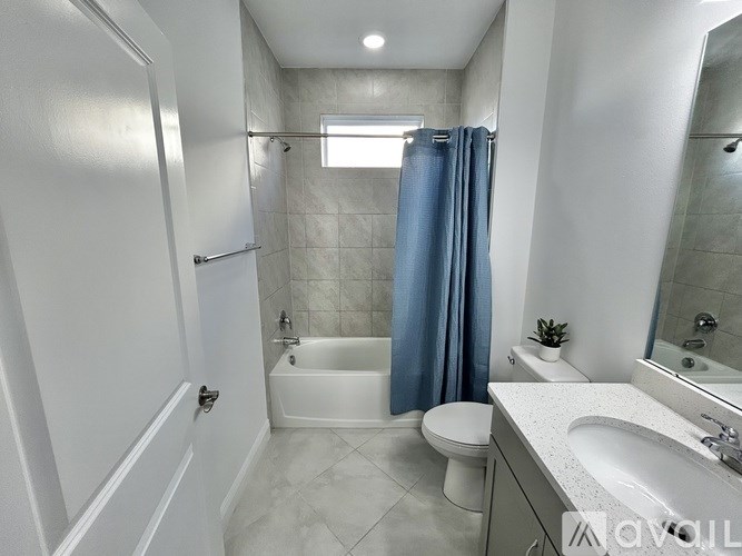 A white bathroom with a blue shower curtain.