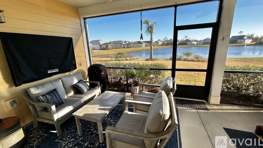 A living room with a view of a lake and houses across the way.