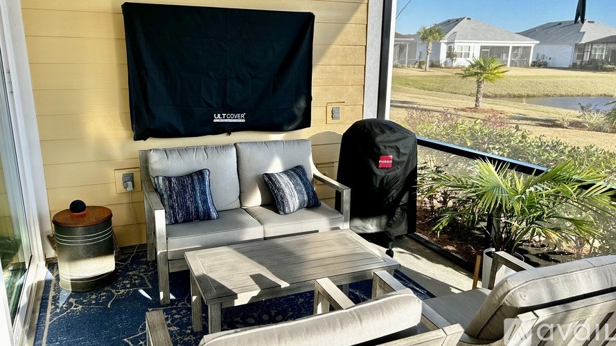 A patio with a couch, coffee table, and a grill.