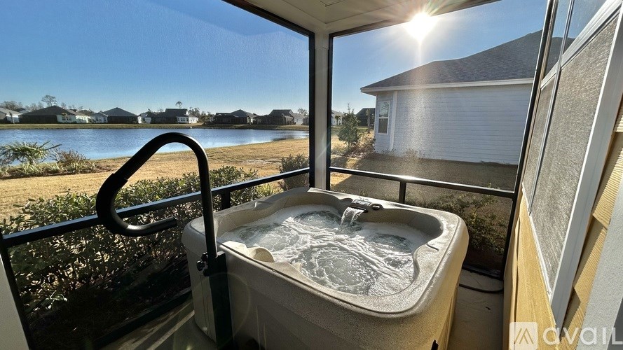 A hot tub is on a balcony with a view of a lake and houses.