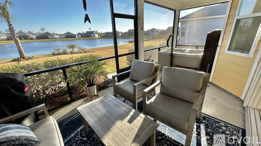 A patio with a chair and a table overlooking a body of water.
