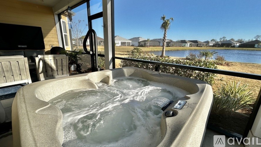 A hot tub with a view of a lake and houses in the background.
