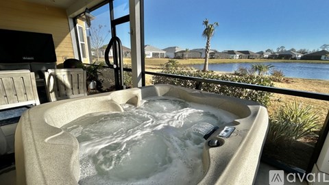 A hot tub with a view of a lake and houses in the background.