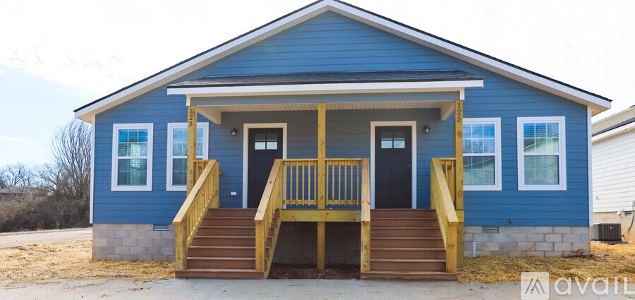 A blue house with a wooden porch and stairs leading to the front door.