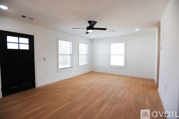 A spacious room with wooden flooring and a ceiling fan.