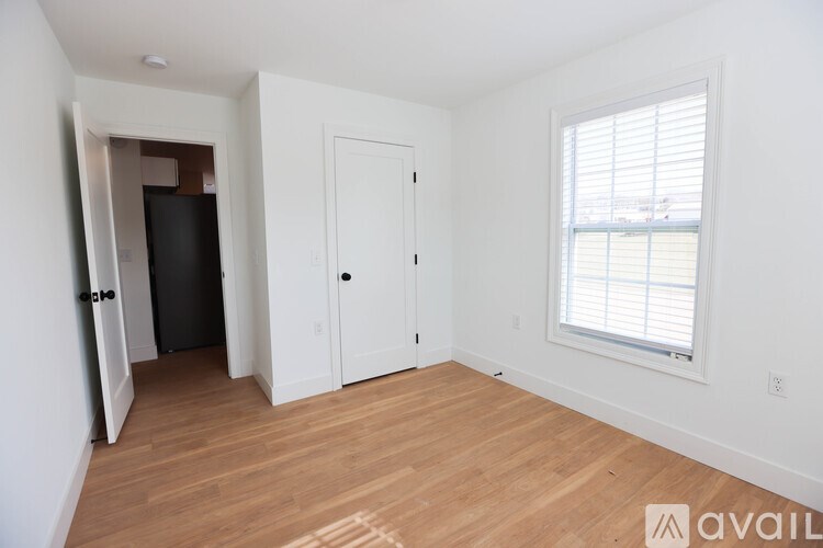 A room with a door, a window, and a wooden floor.