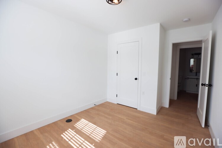 A room with a white door and wooden floor.