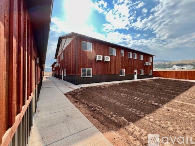 A red building with a brown roof and a white fence in front of it.