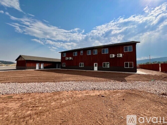 A red barn with a gravel area in front of it.