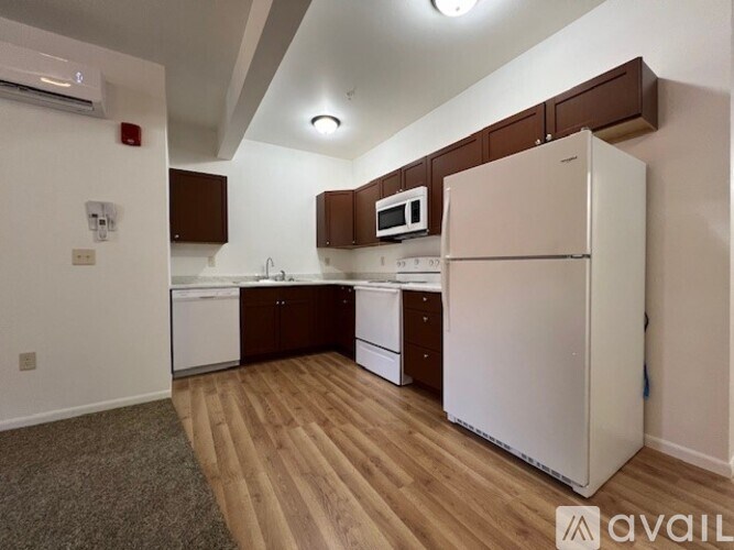 A kitchen with white appliances and brown cabinets.