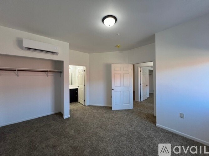 A spacious room with a carpeted floor and an air conditioning unit on the wall.