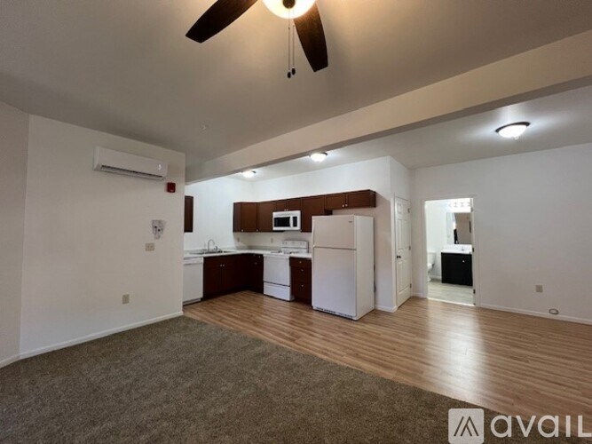 A spacious living room with a kitchen area in the background.