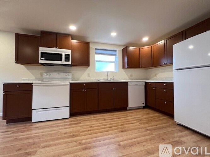 A kitchen with brown cabinets and white appliances.