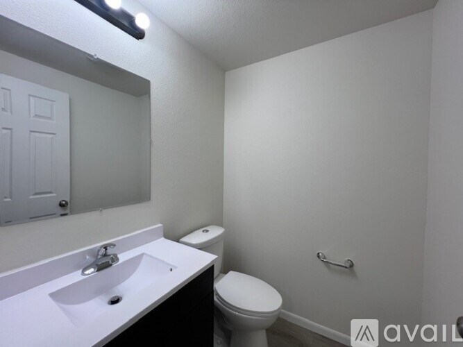 A bathroom with a toilet, sink, and mirror.