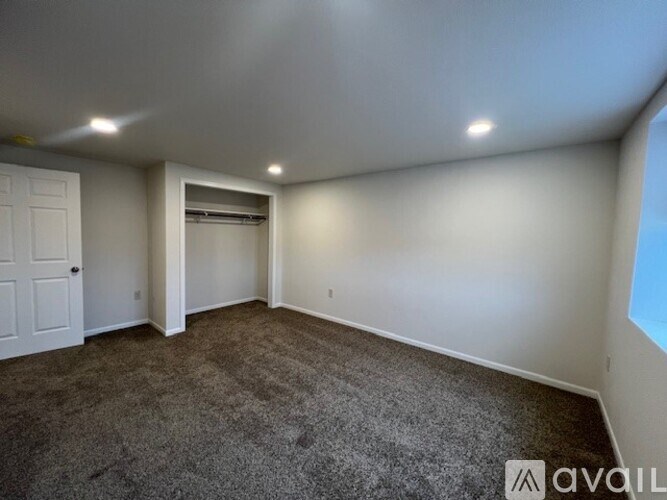 A room with a carpeted floor, a door, and a window.