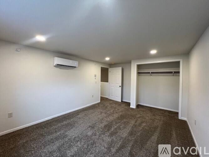 A spacious room with a carpeted floor and a wall-mounted air conditioner unit.
