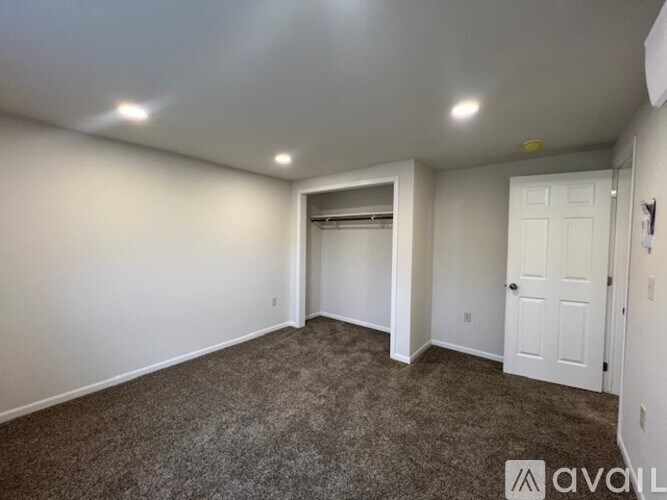 A sparsely furnished room with a carpeted floor and white walls.