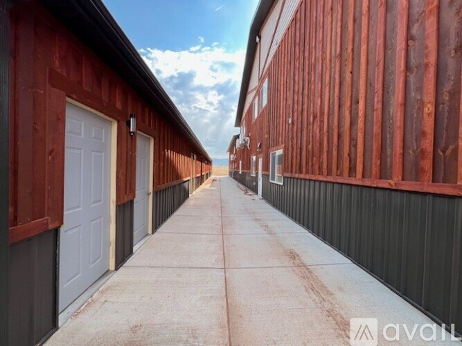 A long, narrow alleyway between two buildings with red and black siding.