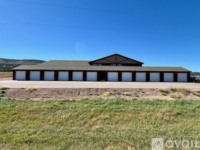 A large building with a grey roof and a car parked in front.