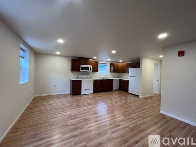 A spacious kitchen with wooden floors and white walls.