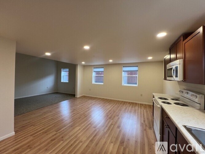 A spacious kitchen with wooden floors and a stove top oven.