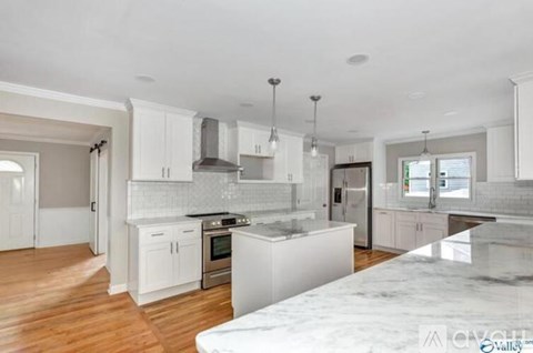 A kitchen with white cabinets and a marble countertop.