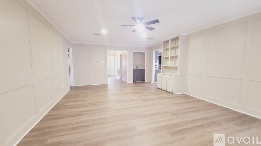 A spacious room with wooden flooring and white walls.